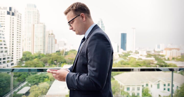 Overseas investor at a laptop with an off-plan brochure and a bank transfer screen, Dubai skyline behind — is it safe to buy property in Dubai as a foreigner?